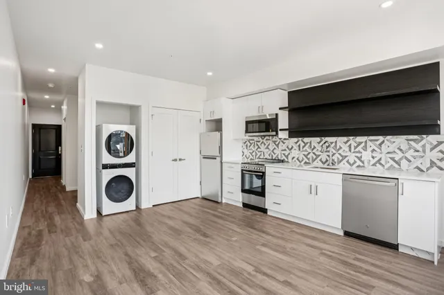 a hall with stainless steel appliances granite countertop a stove and a wooden floors