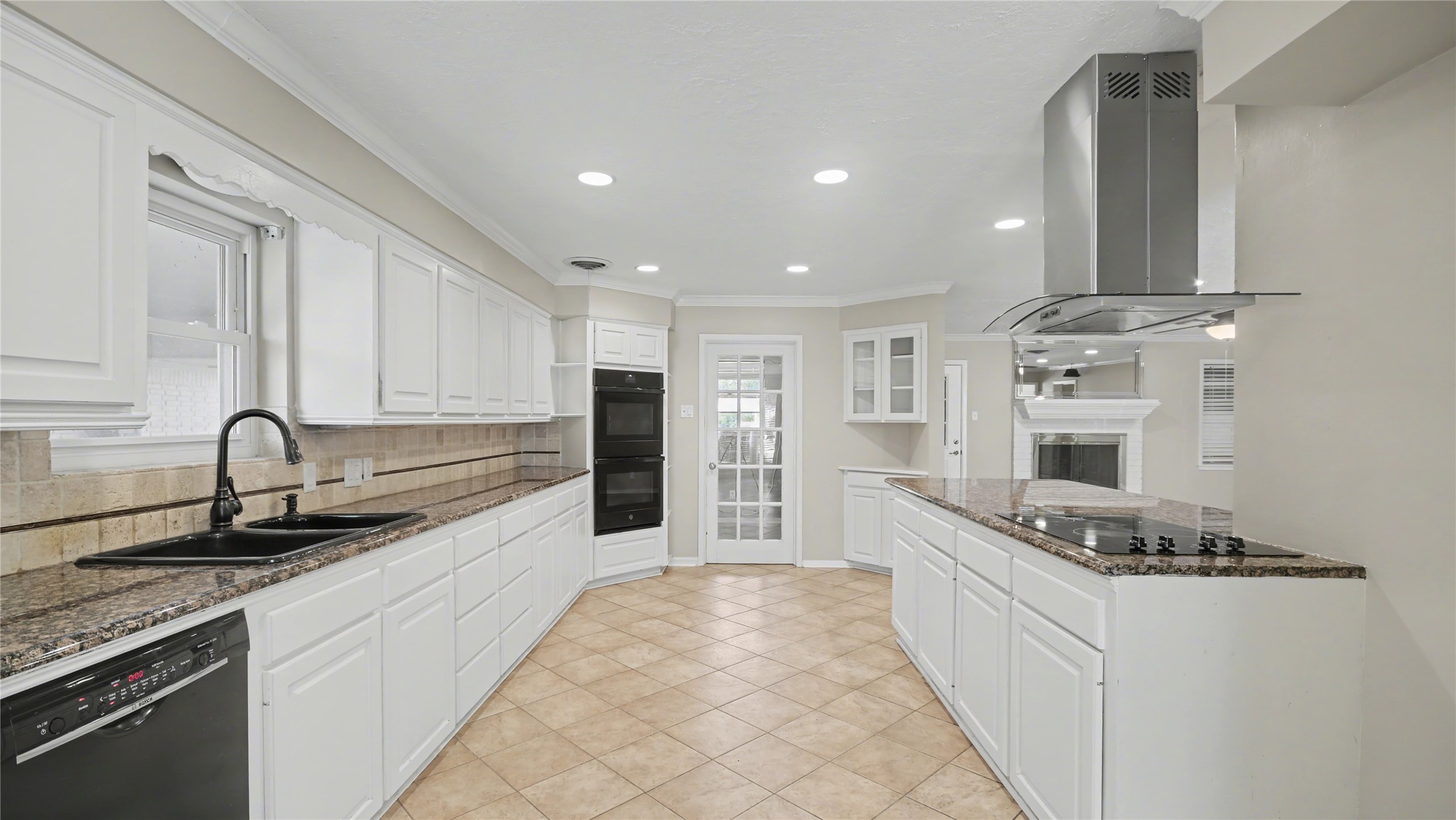 1431 Walnut Lane Houston, TX 77339 - Photo 12 of 46 This spacious kitchen features modern white cabinetry, granite countertops, and stainless steel appliances. It includes a double oven, a sleek cooktop with an overhead hood, and ample storage. The room is bright and inviting, with recessed lighting and a tile floor that complements the contemporary design. A door leads to additional utility room.