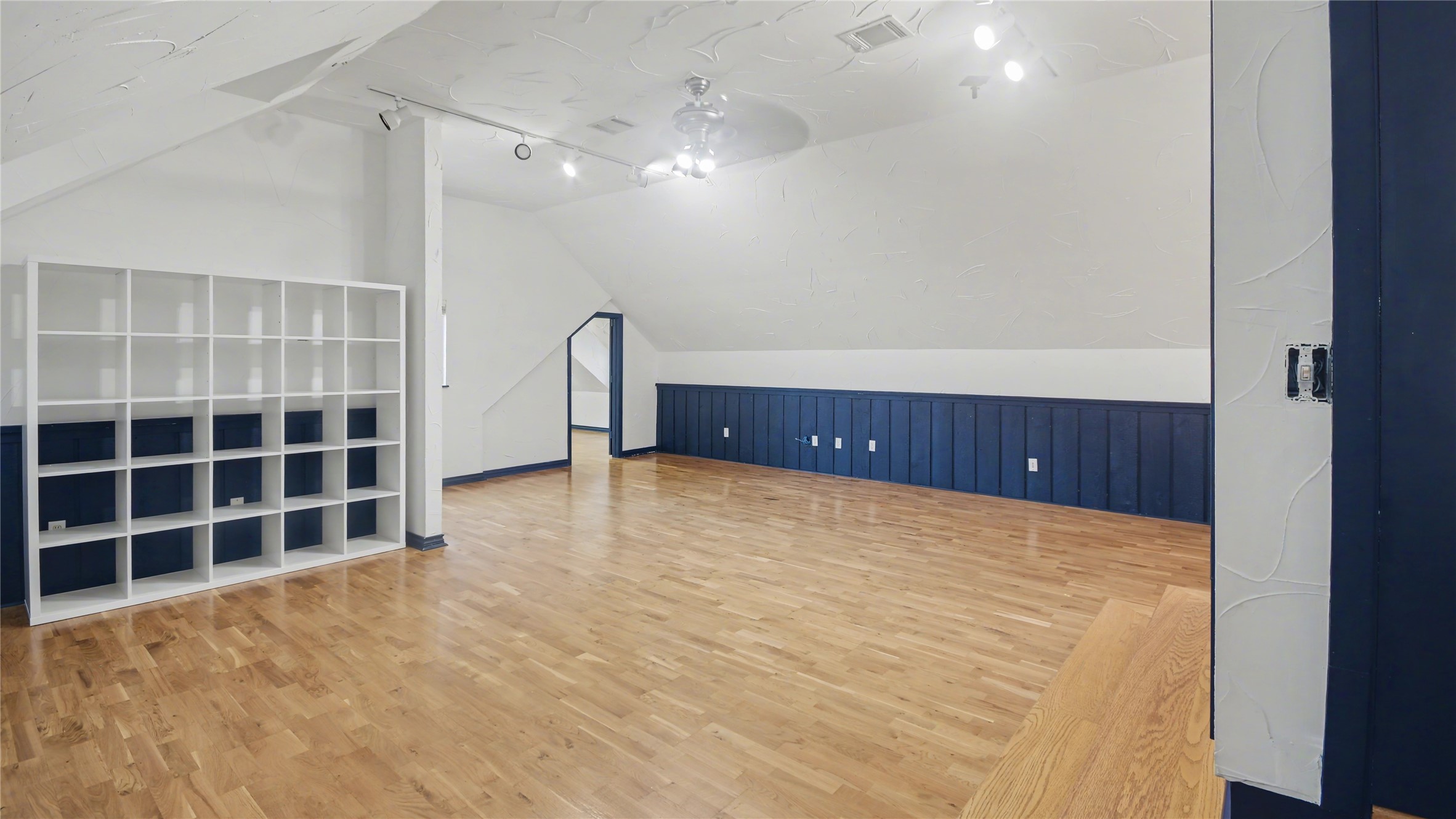 1431 Walnut Lane Houston, TX 77339 - Photo 24 of 46 Upstairs Gameroom features hardwood floors and a white and navy color scheme. It has built-in shelving, recessed lighting, and a ceiling fan, making it a versatile area ideal for a playroom, office, or media space.
