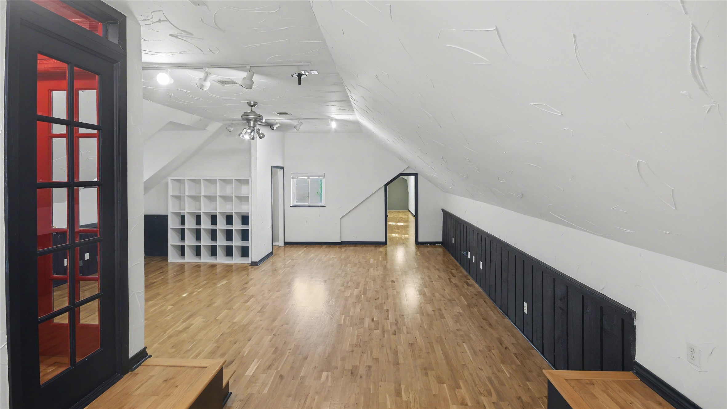 1431 Walnut Lane Houston, TX 77339 - Photo 25 of 46 Gameroom features a sloped ceiling, light wood flooring, and ample built-in storage. Modern track lighting and a ceiling fan provide a bright, airy feel, while a bold red door adds a unique touch. Ideal for a creative studio or additional living space.