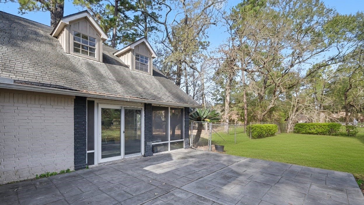 1431 Walnut Lane Houston, TX 77339 - Photo 43 of 46 This photo showcases a charming home exterior with a spacious patio and large windows, set in a lush, tree-filled backyard. Perfect for outdoor relaxation and entertaining.