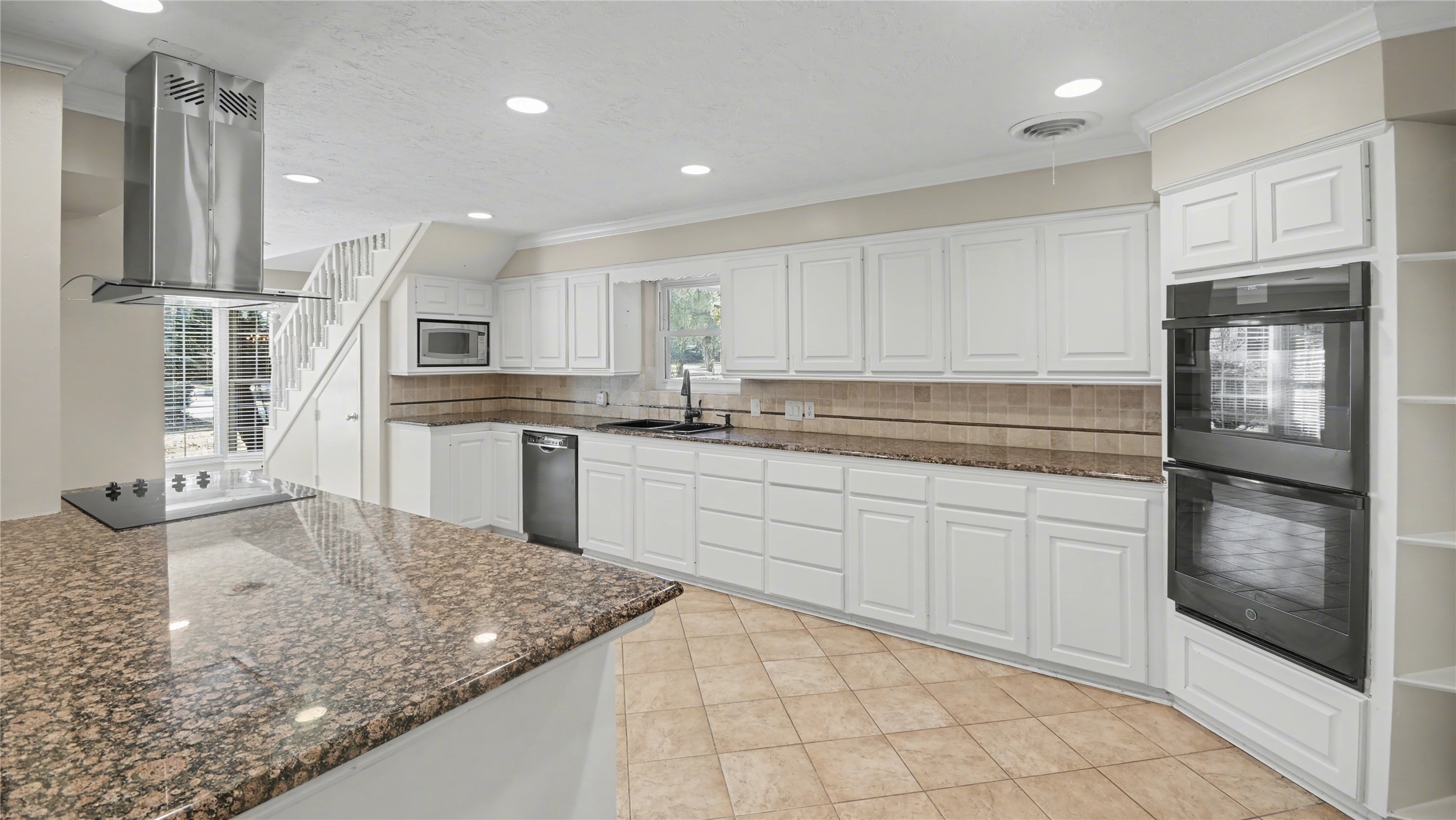 1431 Walnut Lane Houston, TX 77339 - Photo 6 of 47 This spacious kitchen boasts sleek granite countertops, abundant white cabinetry, and modern appliances, offering a bright and inviting space for culinary creativity and family gatherings.