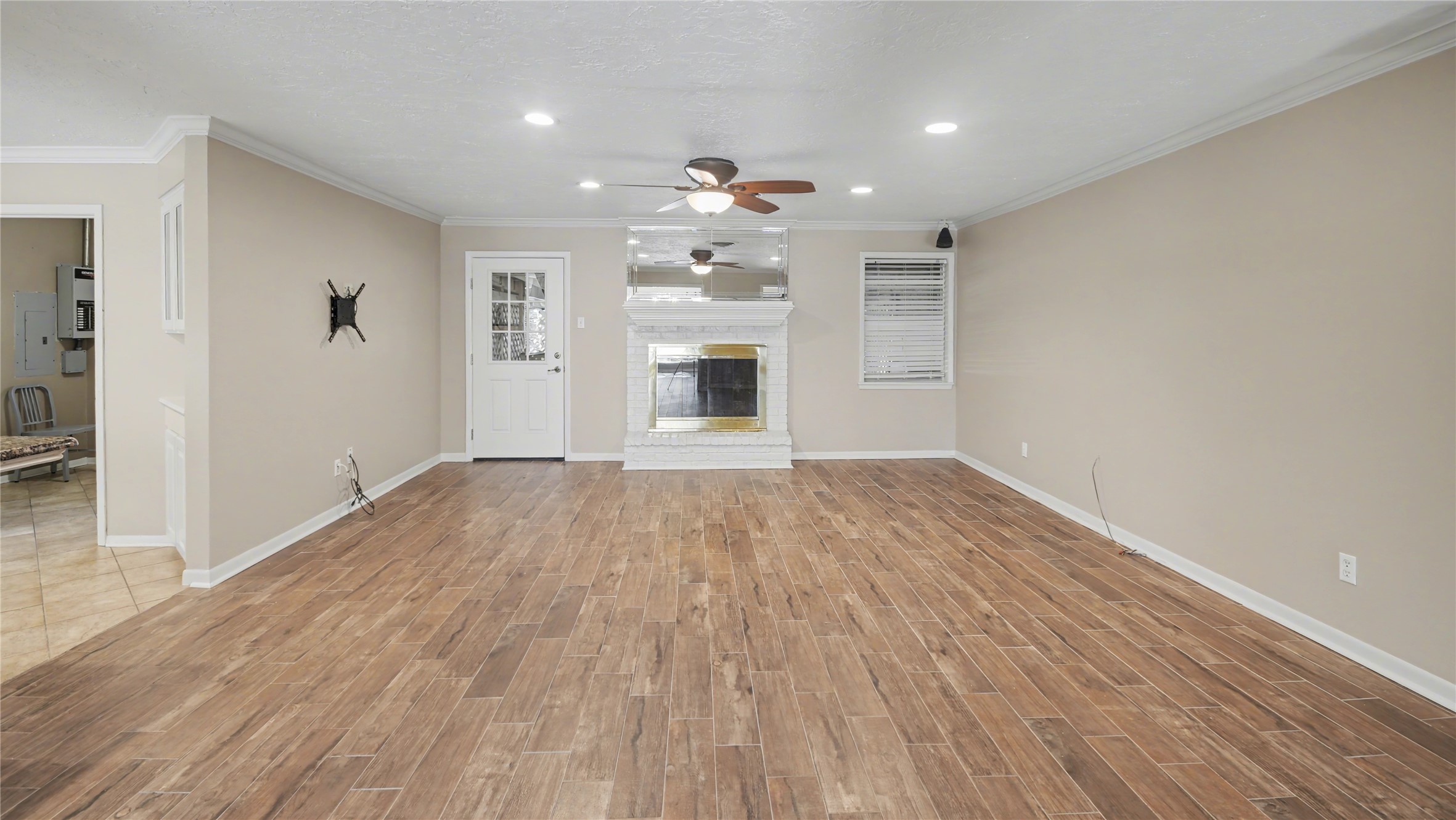 1431 Walnut Lane Houston, TX 77339 - Photo 10 of 46 Step into this inviting living room featuring warm wood-look tile flooring, a cozy brick fireplace, and modern ceiling fans, perfect for creating cherished memories.