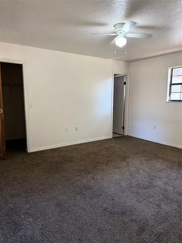 an empty room with a ceiling fan and a window