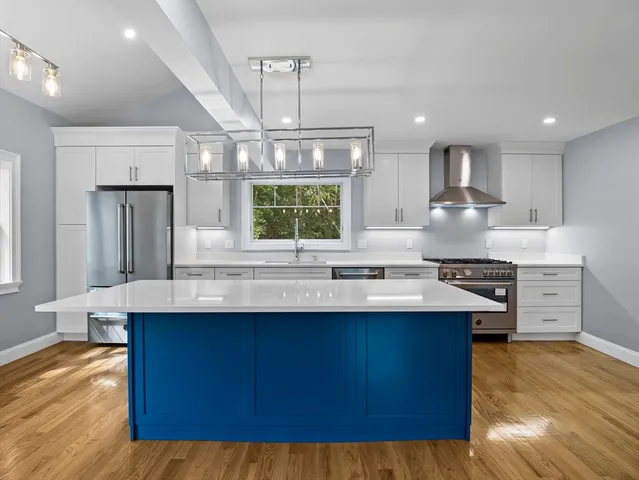a kitchen with kitchen island granite countertop a sink cabinets and wooden floor