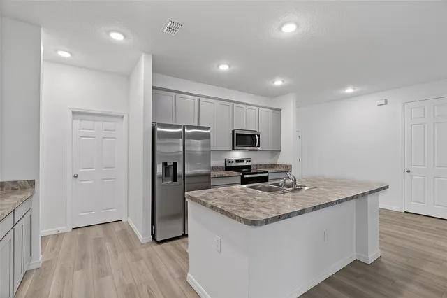 a kitchen with kitchen island granite countertop stainless steel appliances a stove refrigerator and microwave