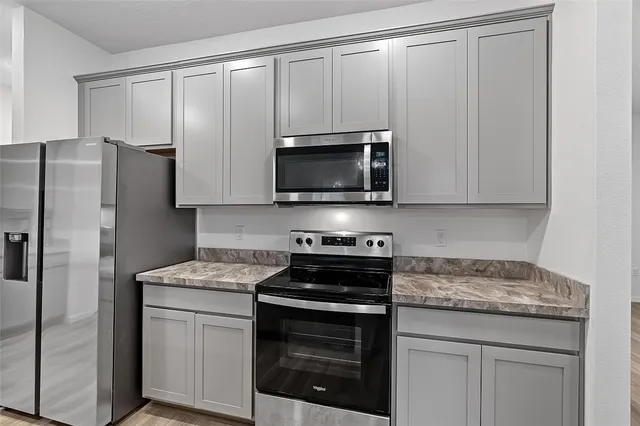 a kitchen with stainless steel appliances granite countertop white cabinets a refrigerator and a stove