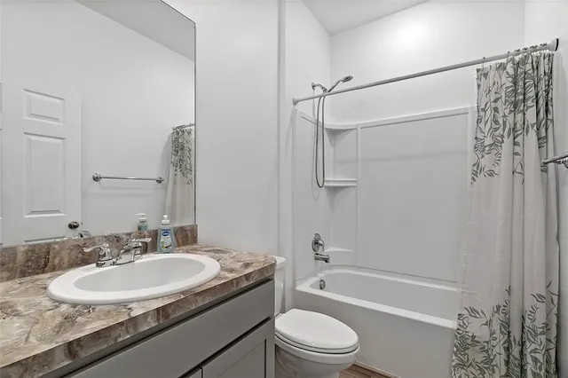 a bathroom with a granite countertop sink a toilet a mirror a bathtub and shower