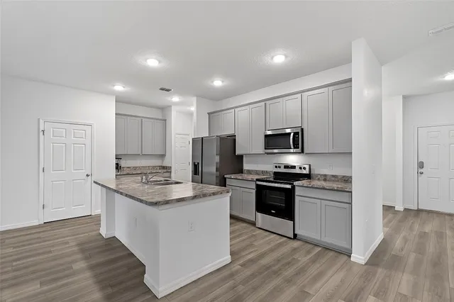 a kitchen with stainless steel appliances granite countertop a stove top oven a sink and a refrigerator