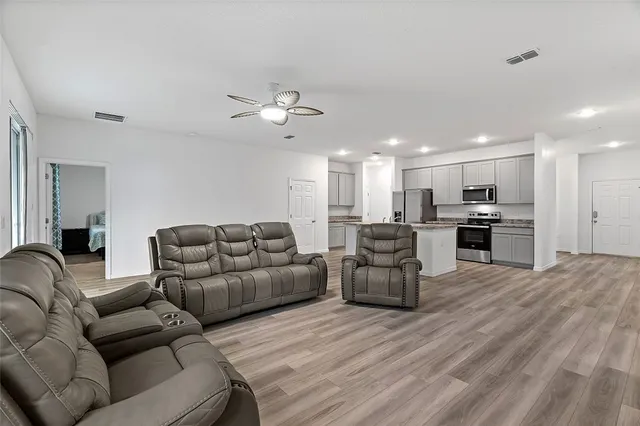 a living room with furniture kitchen view and a chandelier