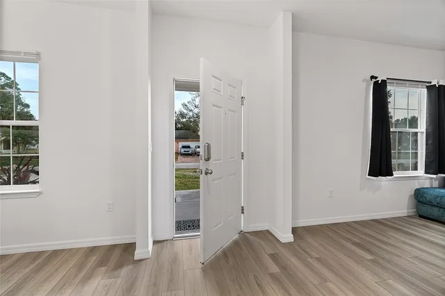 an empty room with wooden floor and windows