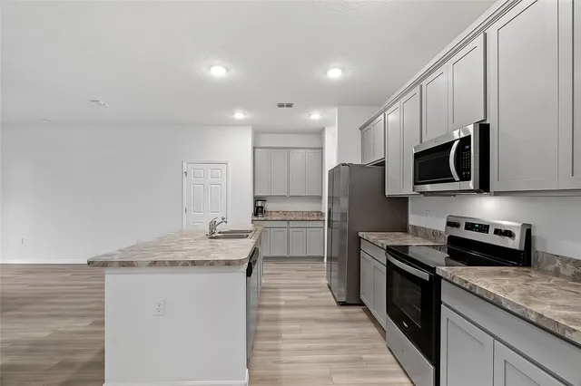 a kitchen with stainless steel appliances granite countertop a sink stove microwave and refrigerator