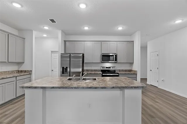 a kitchen with stainless steel appliances granite countertop a sink a stove a refrigerator a center island and cabinets