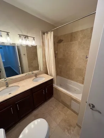 a bathroom with a double vanity sink and mirror with bathtub