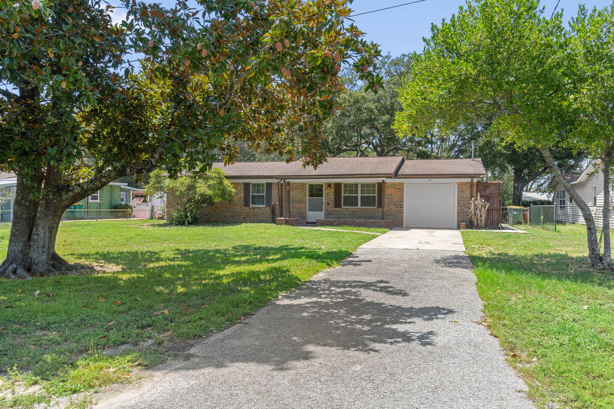 a view of house with a big yard potted plants and large trees