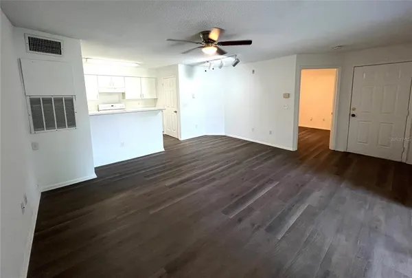 a view of kitchen and empty room with wooden floor