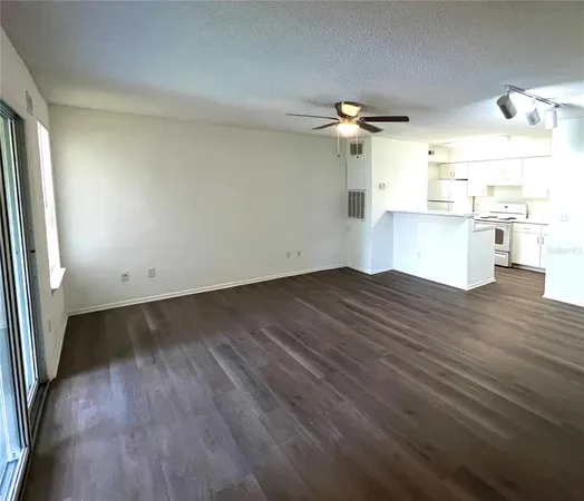 an empty room with wooden floor ceiling fan and window