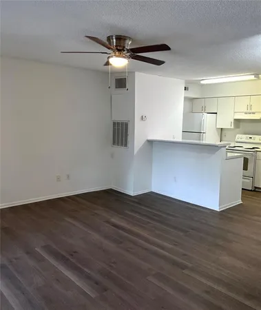 an empty room with wooden floor cabinet and windows