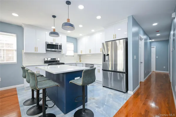 a kitchen with kitchen island stainless steel appliances a sink and a refrigerator