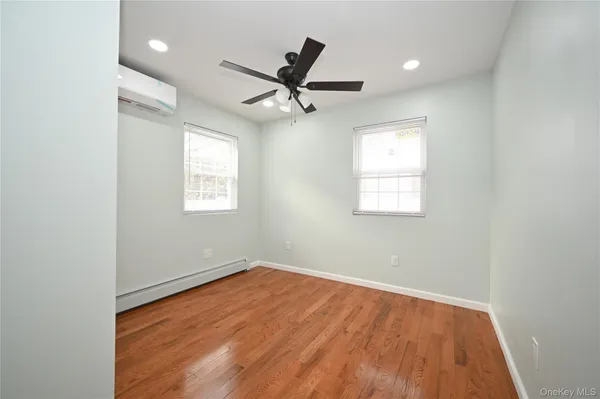 an empty room with wooden floor ceiling fan and windows