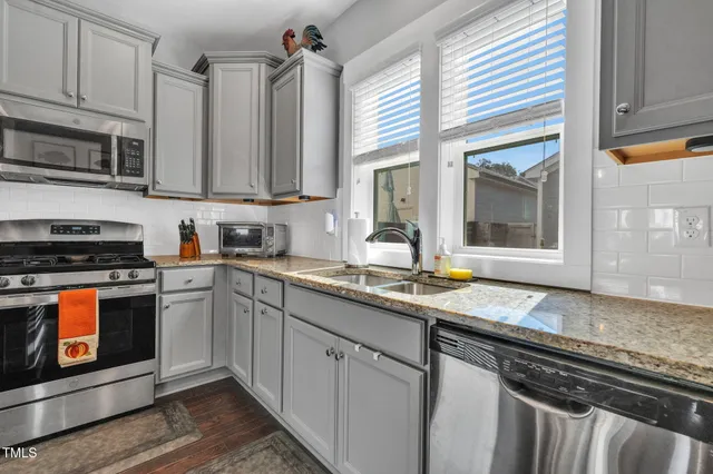 a kitchen with stainless steel appliances granite countertop a sink refrigerator and cabinets