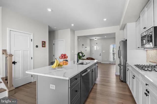 a kitchen with stainless steel appliances a stove refrigerator a sink dishwasher and wooden cabinets with wooden floor