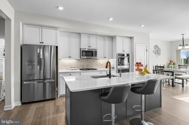 a kitchen with stainless steel appliances granite countertop a refrigerator a stove a sink a dining table and chairs