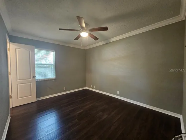 an empty room with wooden floor fan and windows