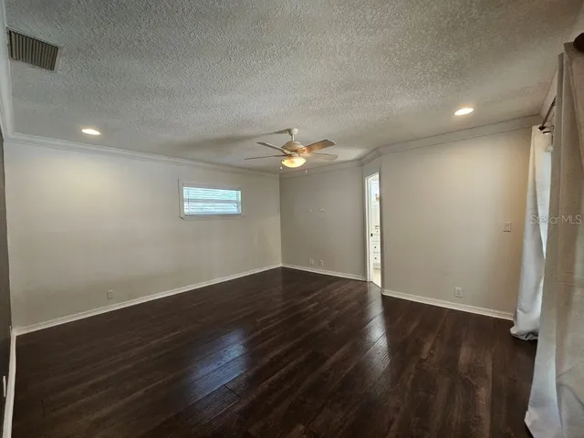 an empty room with wooden floor chandelier fan and windows