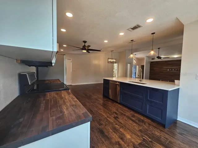 a large kitchen with wooden floor and stainless steel appliances