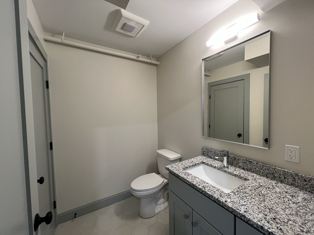 160 Seabury Street, Unit 40 Fall River, MA 02720 - Photo 5 of 13 a bathroom with a granite countertop sink a toilet and a mirror