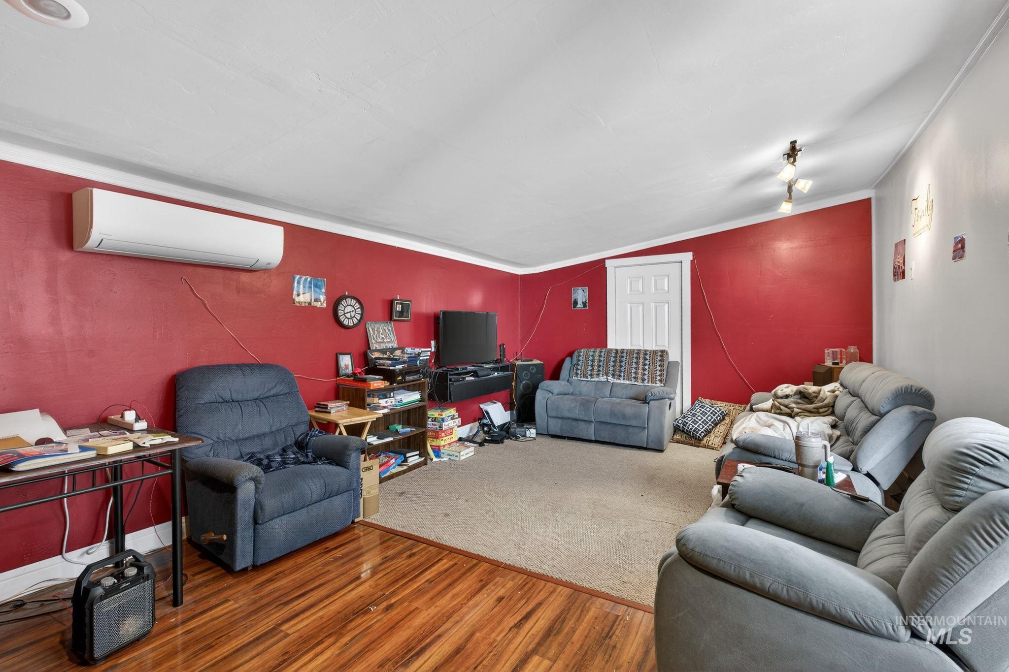 208 South 4th W Street Preston, ID 83263 - Photo 13 of 38 Living area featuring wood finished floors, a wall mounted air conditioner, ornamental molding, and lofted ceiling