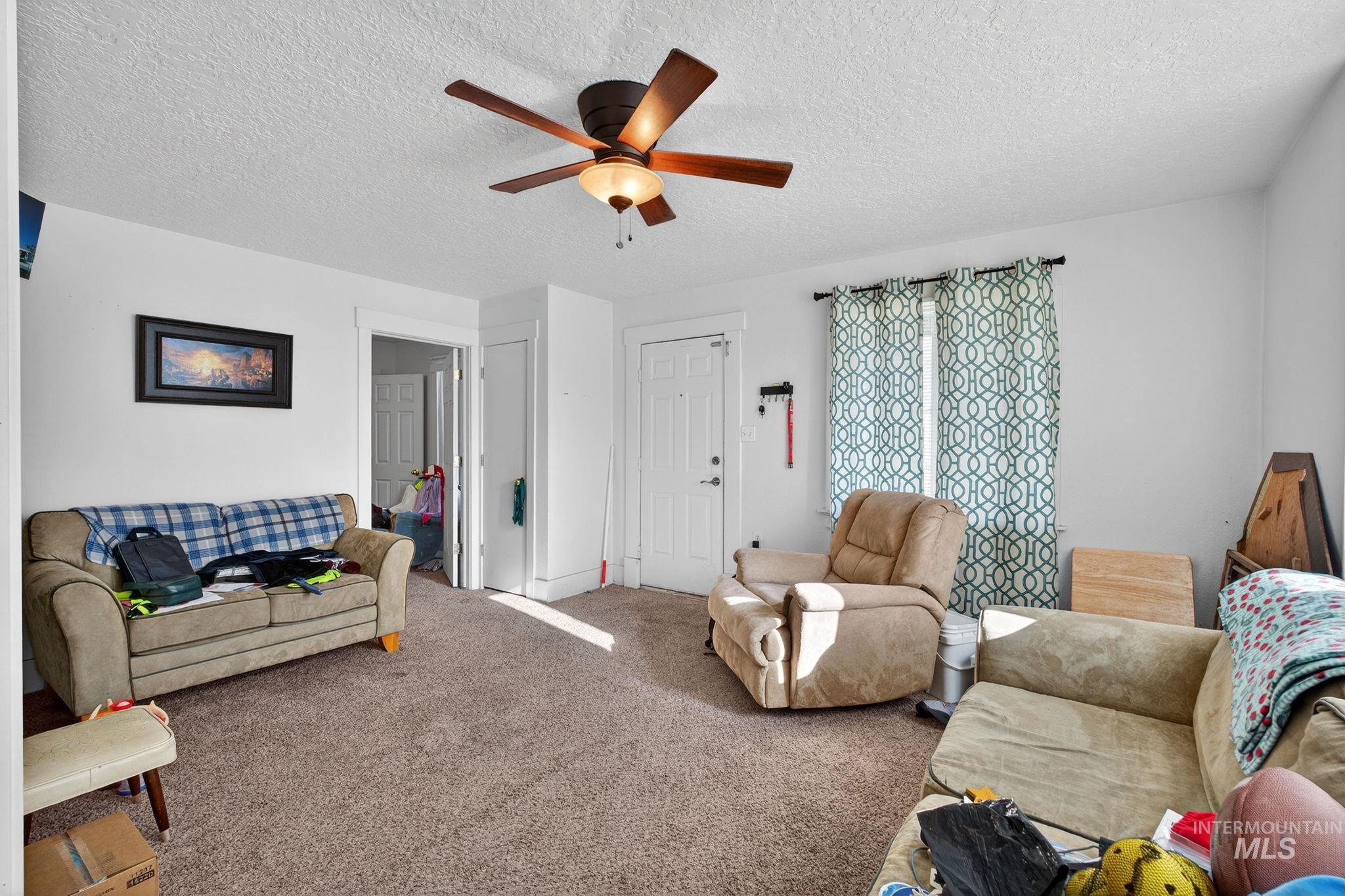 208 South 4th W Street Preston, ID 83263 - Photo 3 of 38 Carpeted living room with a textured ceiling and a ceiling fan