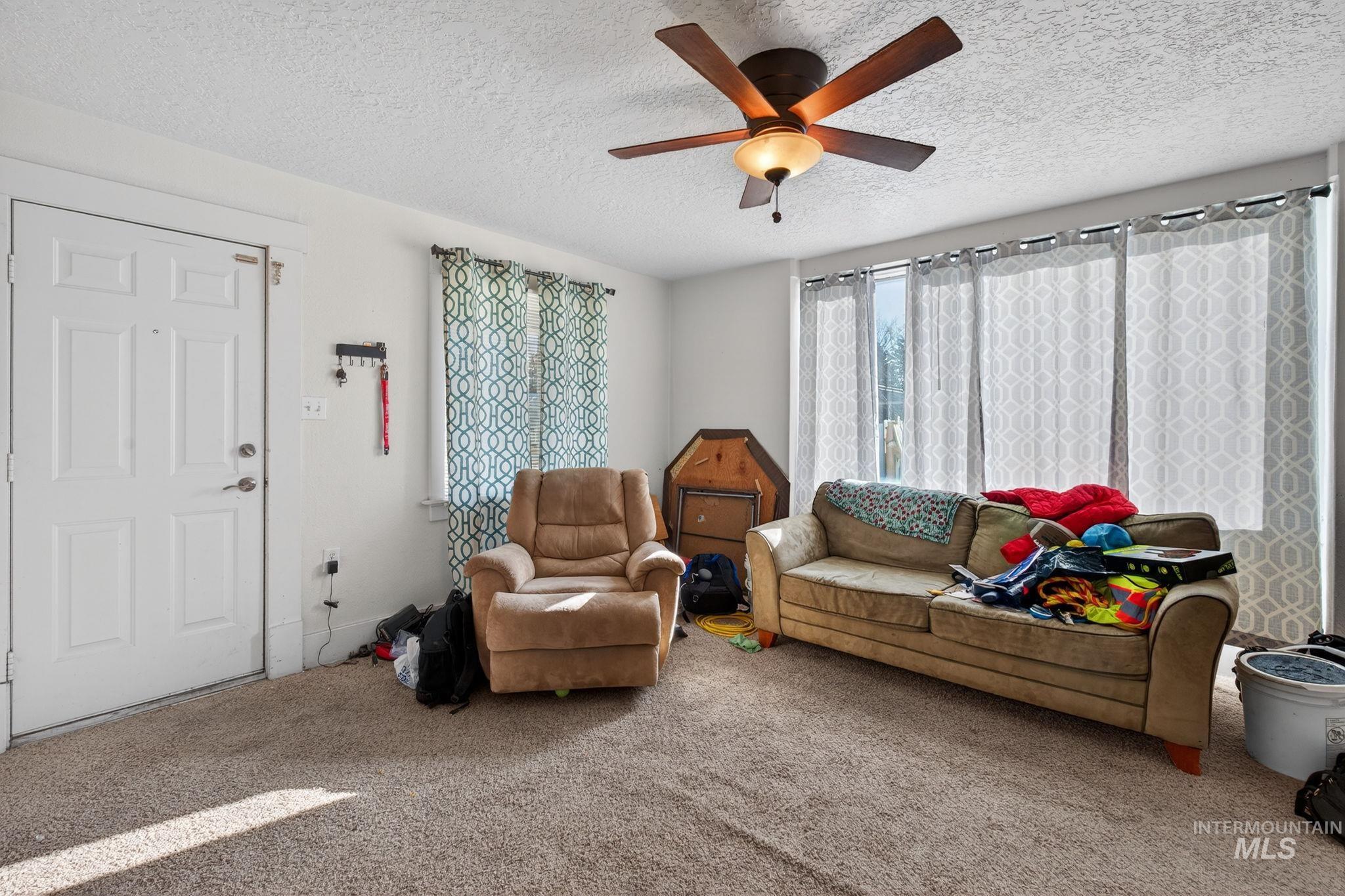 208 South 4th W Street Preston, ID 83263 - Photo 4 of 38 Carpeted living room featuring a textured ceiling and a ceiling fan