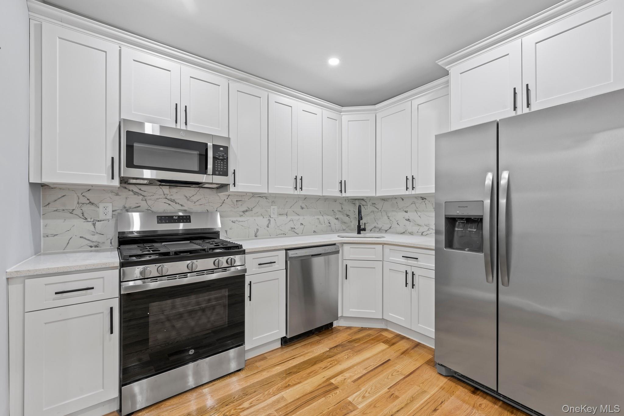 a kitchen with cabinets stainless steel appliances and wooden floor