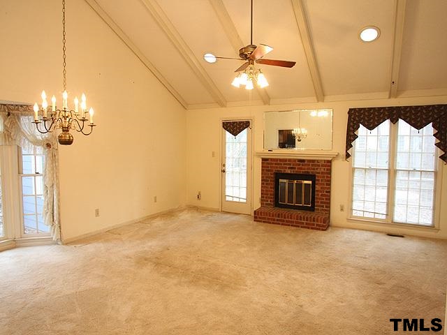 1213 Oakside Court Raleigh, NC 27609 - Photo 2 of 13 a view of a livingroom with a fireplace a chandelier and windows
