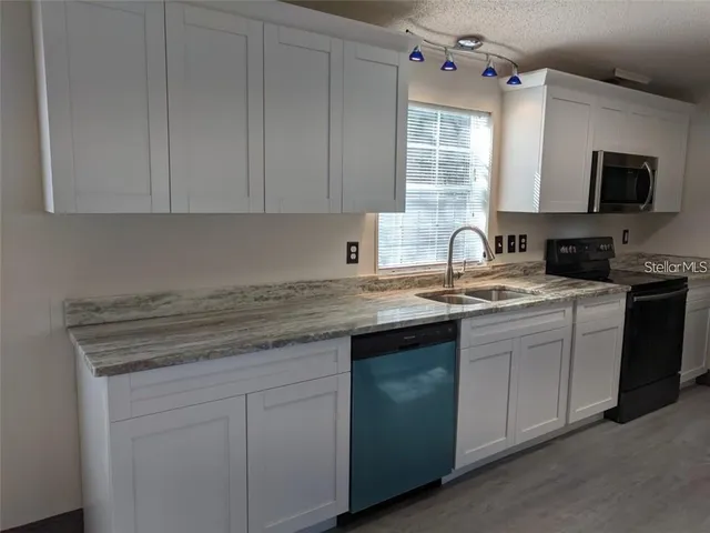 a kitchen with granite countertop white cabinets sink and dishwasher