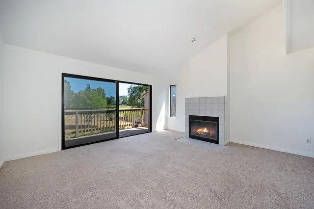 a view of an empty room with a fireplace and a window