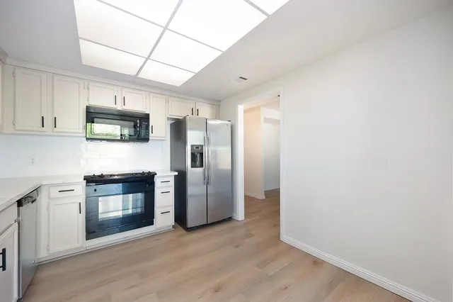 a kitchen with granite countertop a refrigerator and a stove top oven