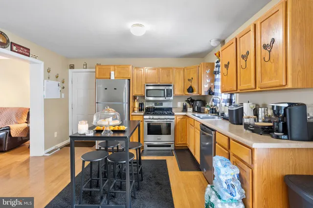 a kitchen with stainless steel appliances a stove top oven a sink a dining table and chairs