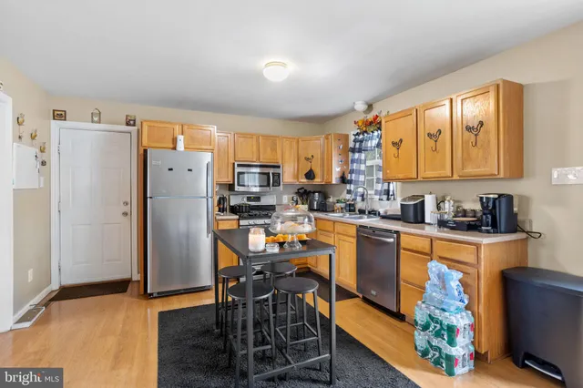 a kitchen with stainless steel appliances a refrigerator a sink a stove a table and chairs