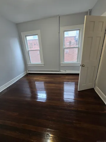 a view of hallway with window and wooden floor