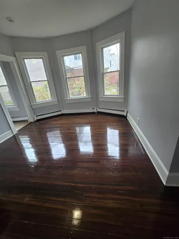 a view of an empty room with wooden floor and window