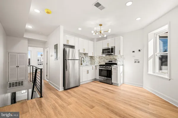 a kitchen with stainless steel appliances kitchen island granite countertop a refrigerator stove top oven and cabinets