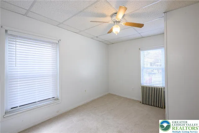 an empty room with windows and fan