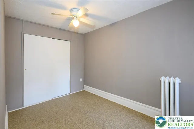 an empty room with a fan & a window