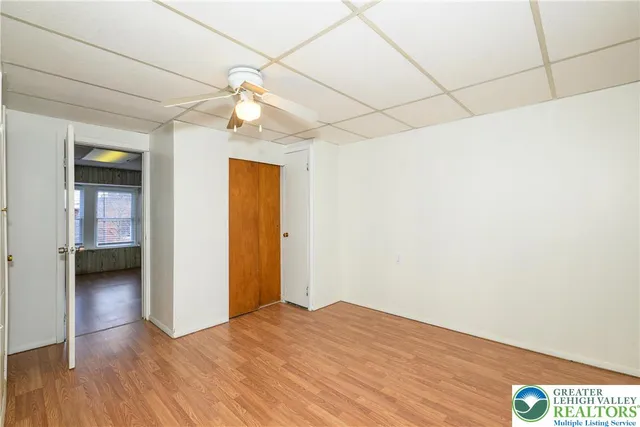 a view of empty room with wooden floor and fan