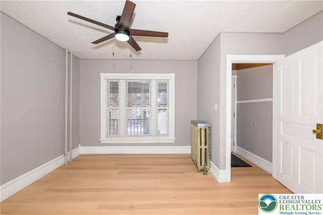 a view of an empty room with window and wooden floor