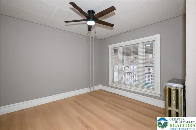 a view of an empty room with a window and wooden floor