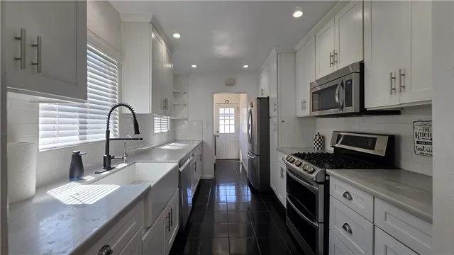 a kitchen with granite countertop a sink stainless steel appliances and cabinets